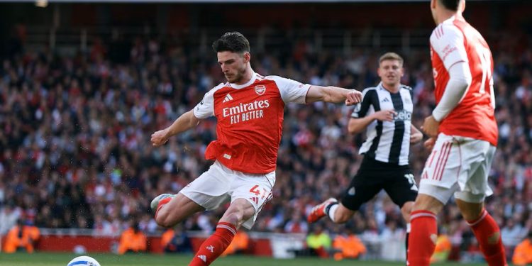 Declan Rice shoots with a Newcastle player in the background